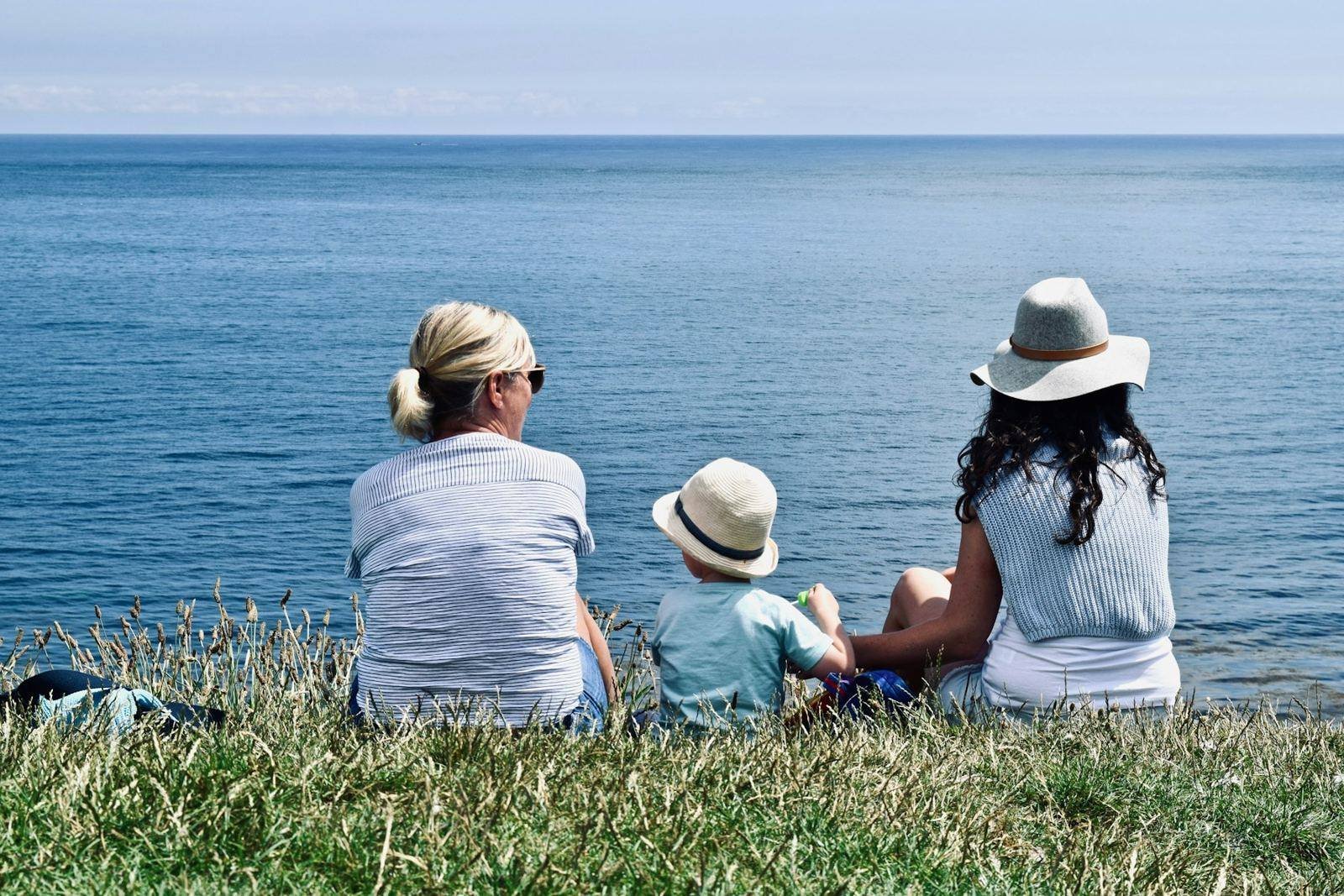 A family sitting together on a clifftop looking out to sea